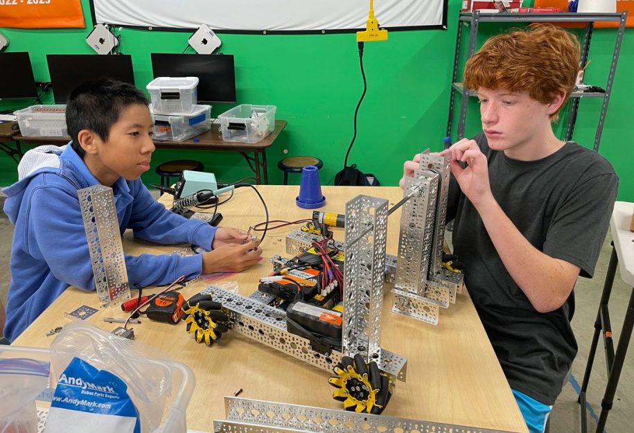 Two male students work together to build a robot in FTC summer programming